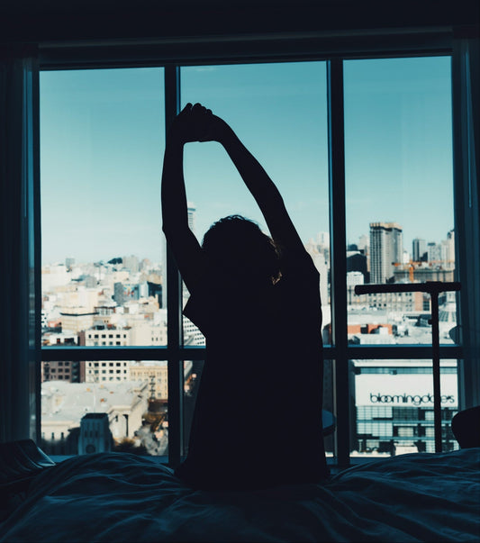 A woman waking up refreshed in from of a city skyline