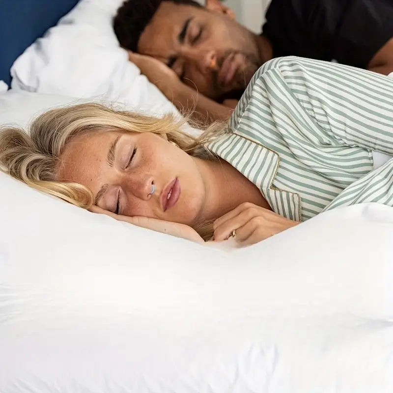 Couple sleeping peacefully in bed with white bedding