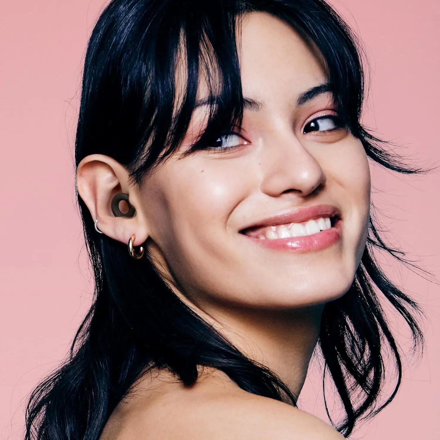 Woman wearing earrings with a pink background