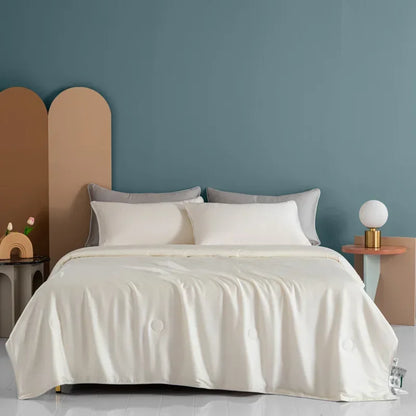 Bed with white bedding and gray pillows against a blue wall
