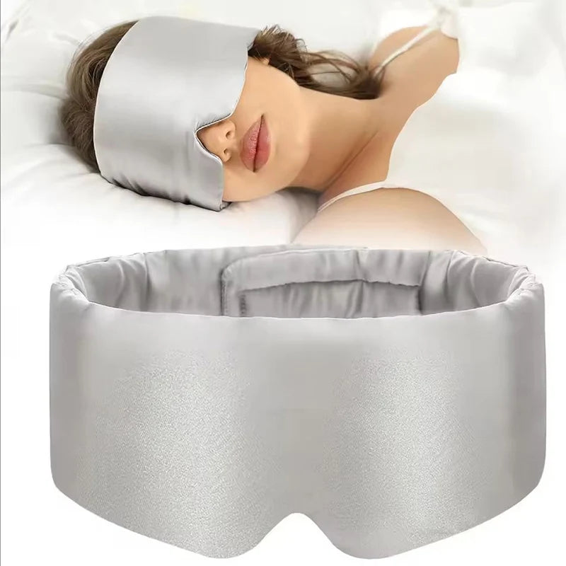 Person wearing a gray sleep mask with a matching pillow on a white background