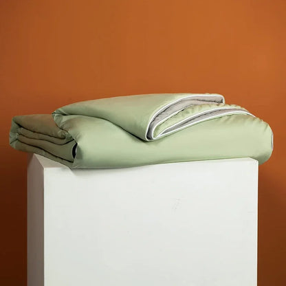 Folded green blanket on a white pedestal against an orange background