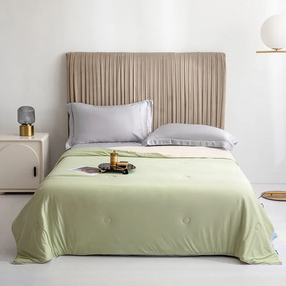 Bed with green bedding and beige headboard in a minimalistic bedroom setting.