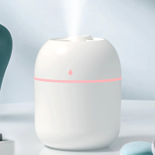 White essential oil diffuser with a pink light on a blurred background