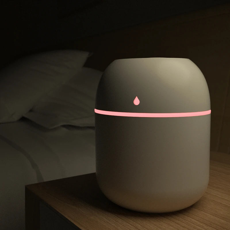 Humidifier with a pink light on a wooden nightstand in a dark room