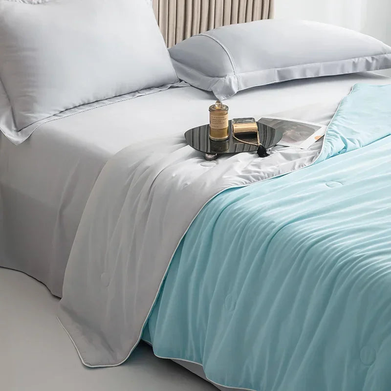Bed with white bedding and a light blue throw blanket, featuring a small tray with items on a nightstand.