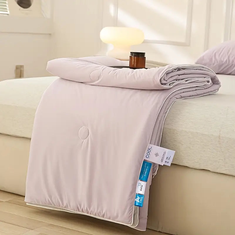 Light gray comforter on a bed with a visible tag in a bedroom setting