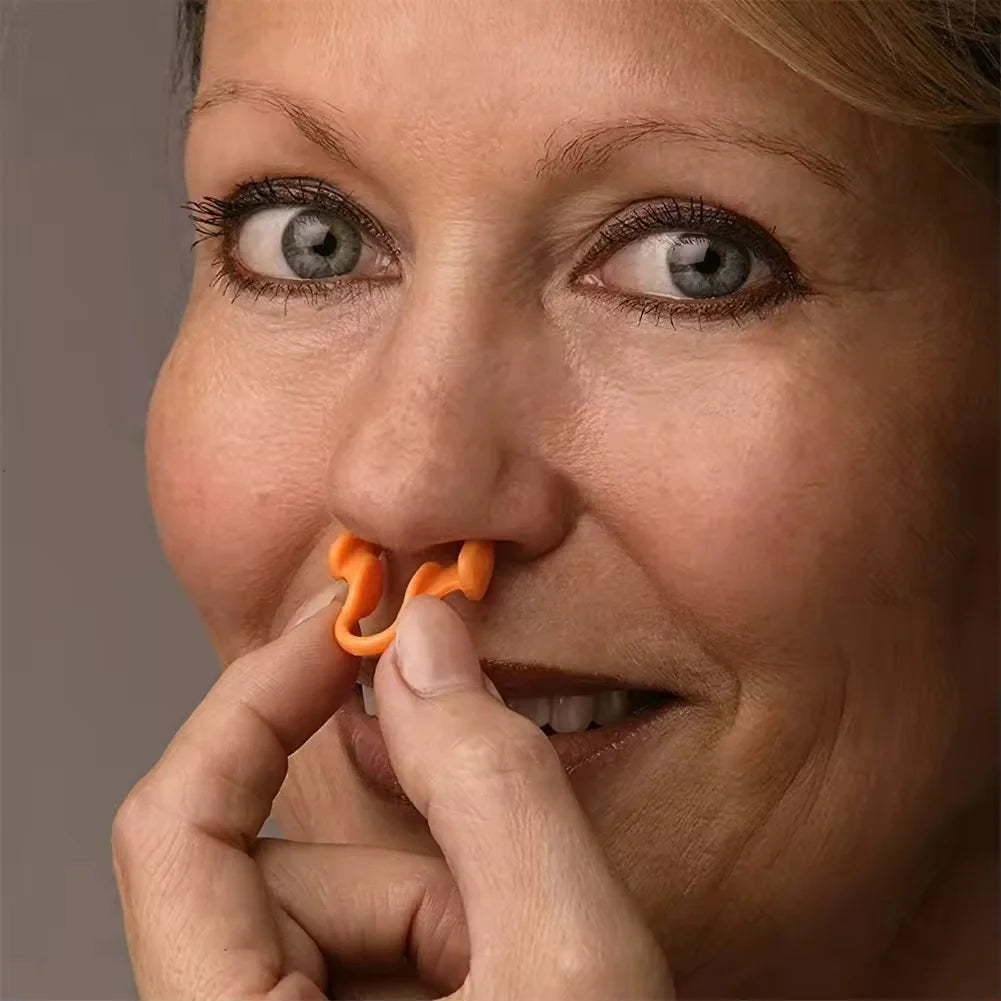 Close-up of a woman using an orange nasal strip on a plain background