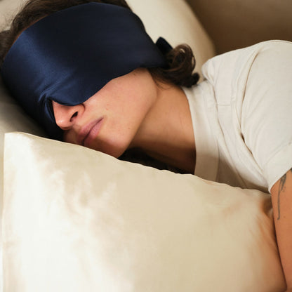 Person sleeping with a blue sleep mask on and a beige pillow. 